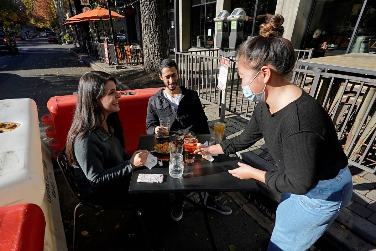 Server Tami Bat, right, brings drinks to Ranim Abaad, left, and Joey Bettencourt, right, having ...