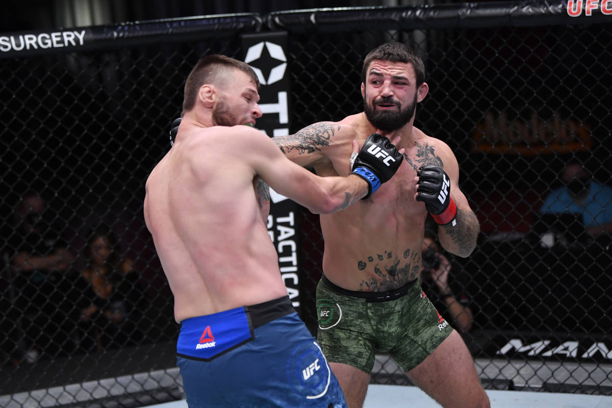 (R-L) Mike Perry punches Tim Means in their welterweight bout during the UFC 255 event at UFC A ...