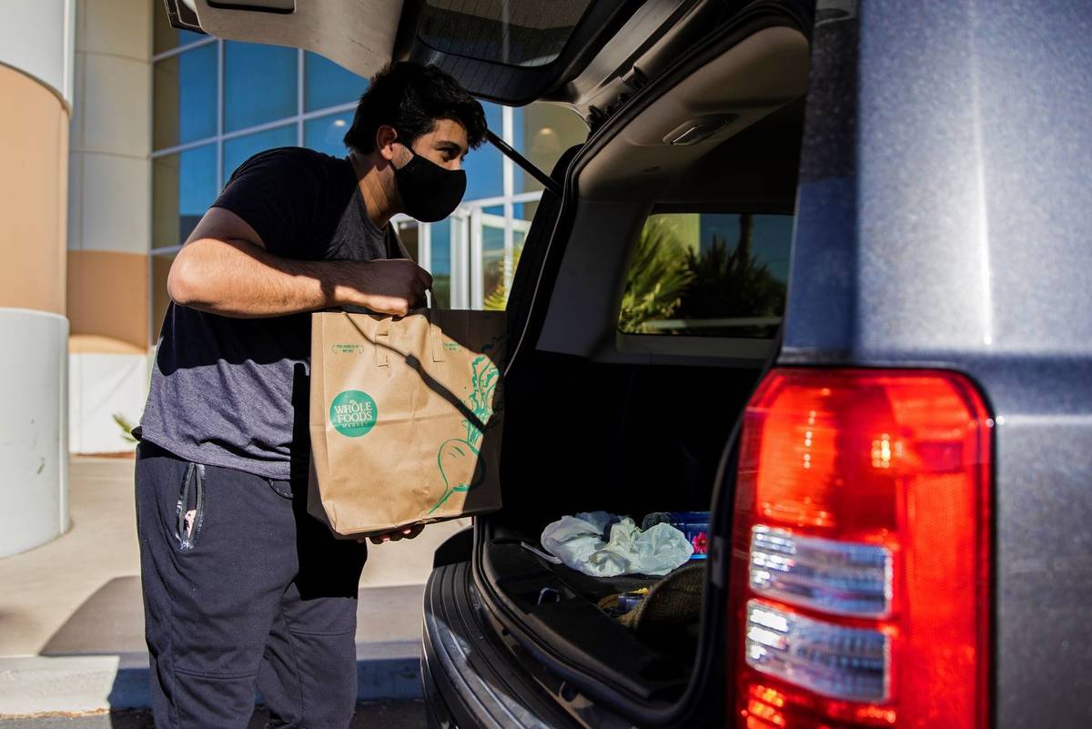 Logistics worker Tristan Sanchez delivers bags of donated food to a vehicle during a food drive ...
