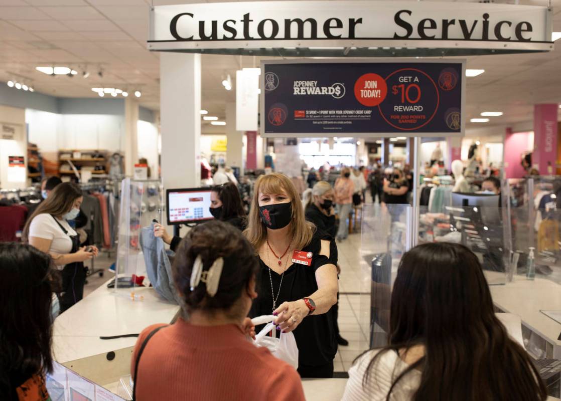 J.C. Penney cashier Debbie Steinberg, middle, checks out customers during Black Friday at the s ...