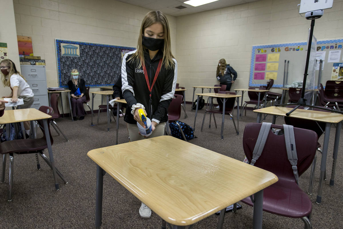 In this Sept. 24, 2020, file photo, Eisley Wheat, 12, center, sprays down a desk in her 6th gr ...