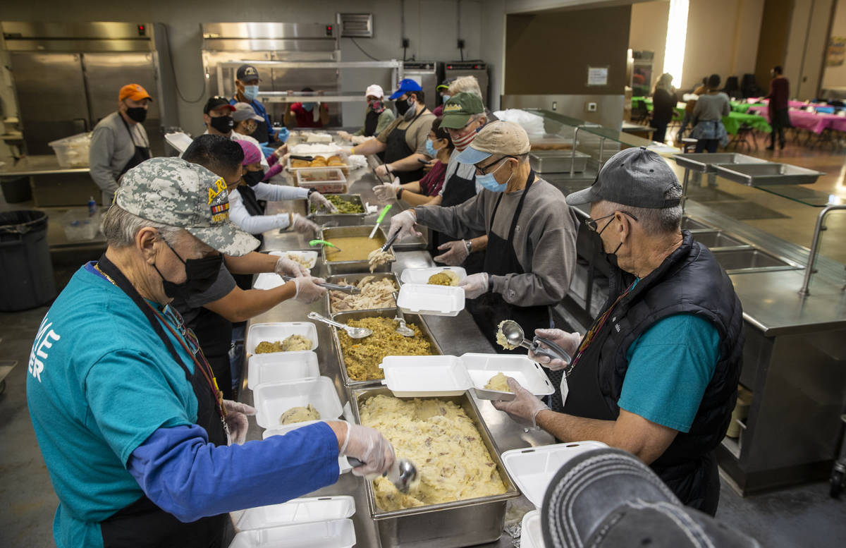 John Meyer, left, and Michael McMahan, right, join other volunteers in serving up a Thanksgivin ...