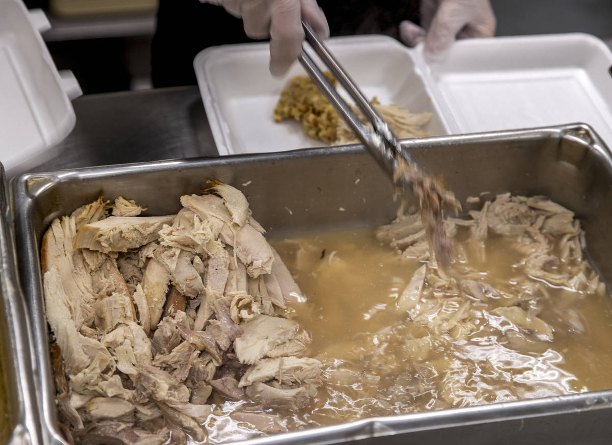 Volunteers serve up turkey from Capriottiճ Sandwich Shop as part of a Thanksgiving meal a ...