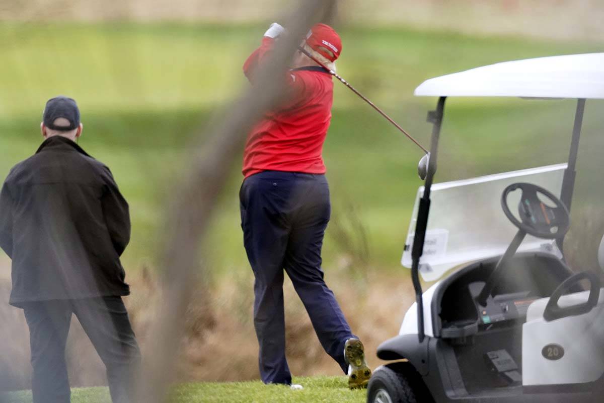 President Donald Trump takes a practice swing as he plays golf at Trump National Golf Club, Fri ...