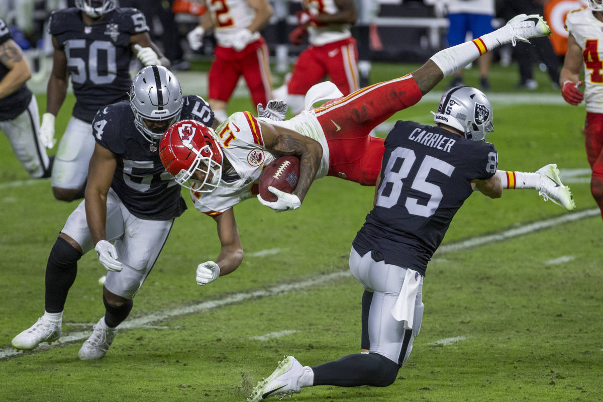 Kansas City Chiefs wide receiver Demarcus Robinson (11, center) is upended by Las Vegas Raiders ...
