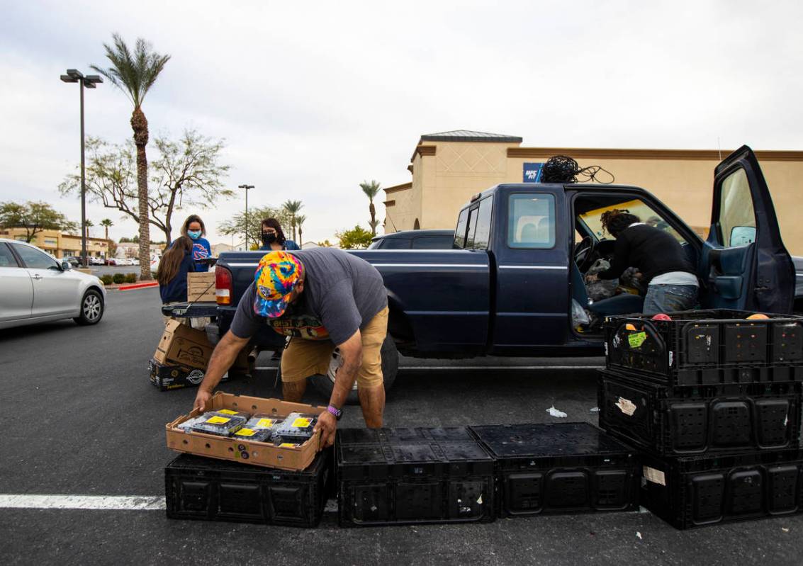 Zach Lopez, left, assists Amber Stevenson in giving out food at a shopping center in Las Vegas ...