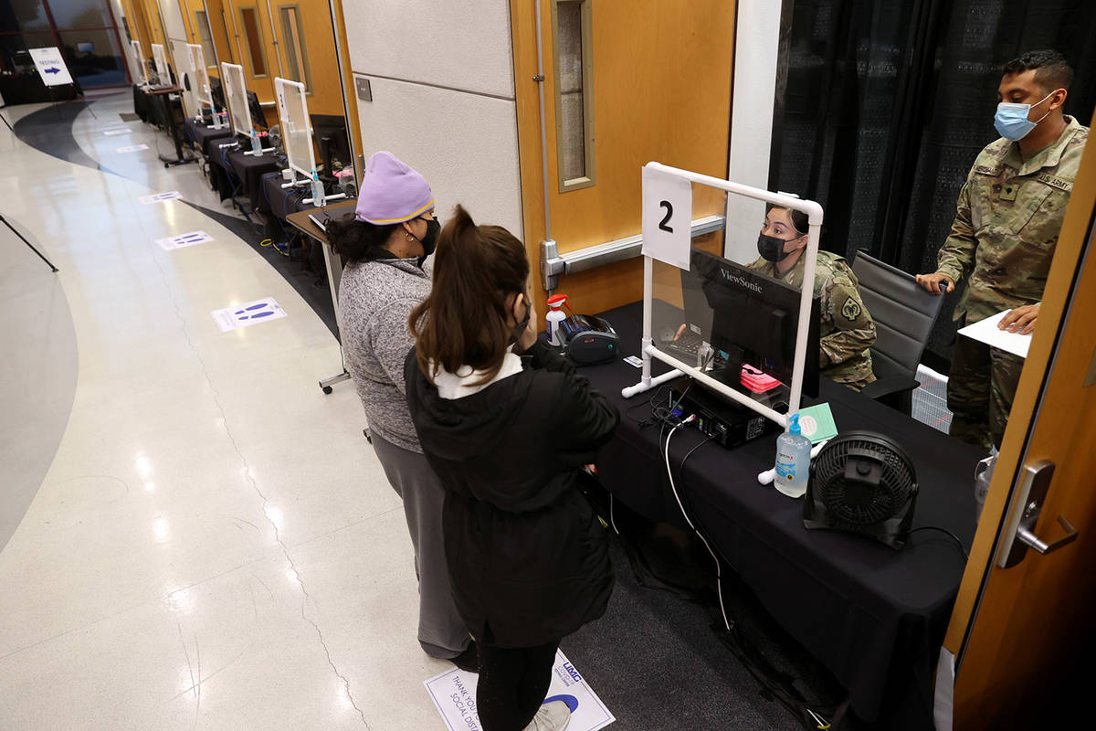 Nevada National Guard specialists Alondra Felix and Daniel Merchant check in Ana Pena, left, an ...