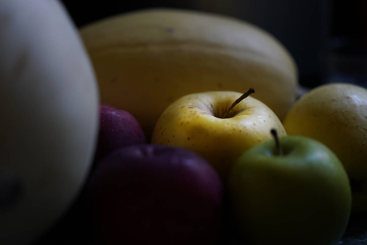 Apples, a melon and a squash sit in the late afternoon light Wednesday, Nov. 11, 2020, on a cou ...