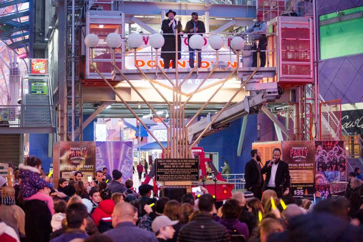 Rabbi Shea Harlig lights the menorah for the start of Hanukkah as David Dahan recites blessings ...