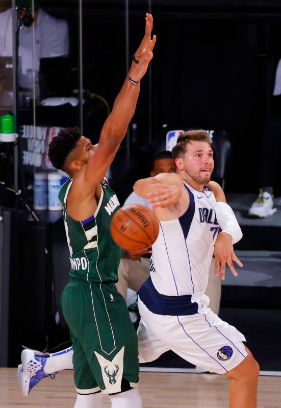 Dallas Mavericks' Luka Doncic, right, passes against Milwaukee Bucks' Giannis Antetokounmpo, le ...