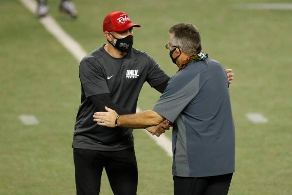 UNLV head coach Marcus Arroyo, left, shakes hands with Hawaii head coach Todd Graham at the end ...