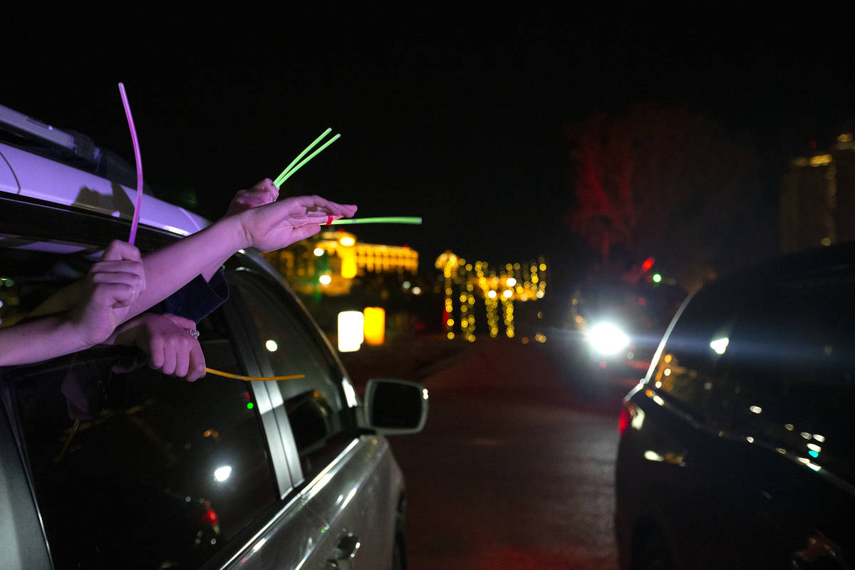 Members of the Jewish community wave glow sticks during a drive-in Hanukkah event hosted by the ...