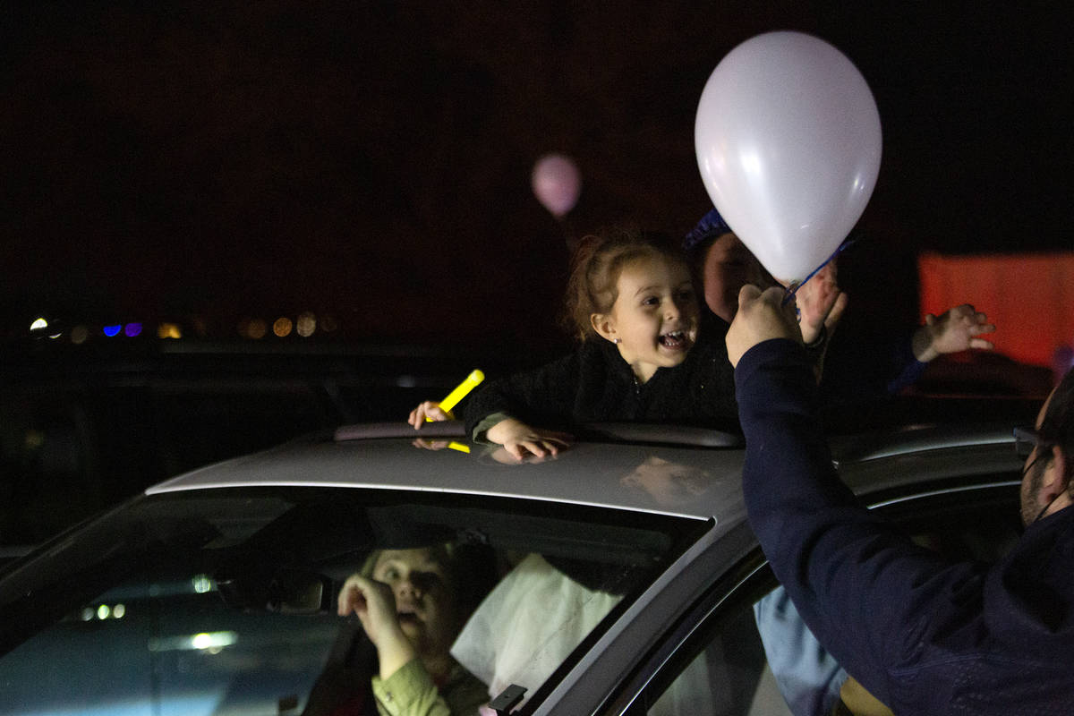 Sophie Nisgoda, 4, accepts a balloon during a drive-in Hanukkah event at the Israeli American C ...