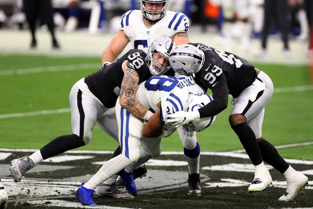 Raiders defensive end Maxx Crosby (98) and defensive end Arden Key (99) tackle Indianapolis Col ...