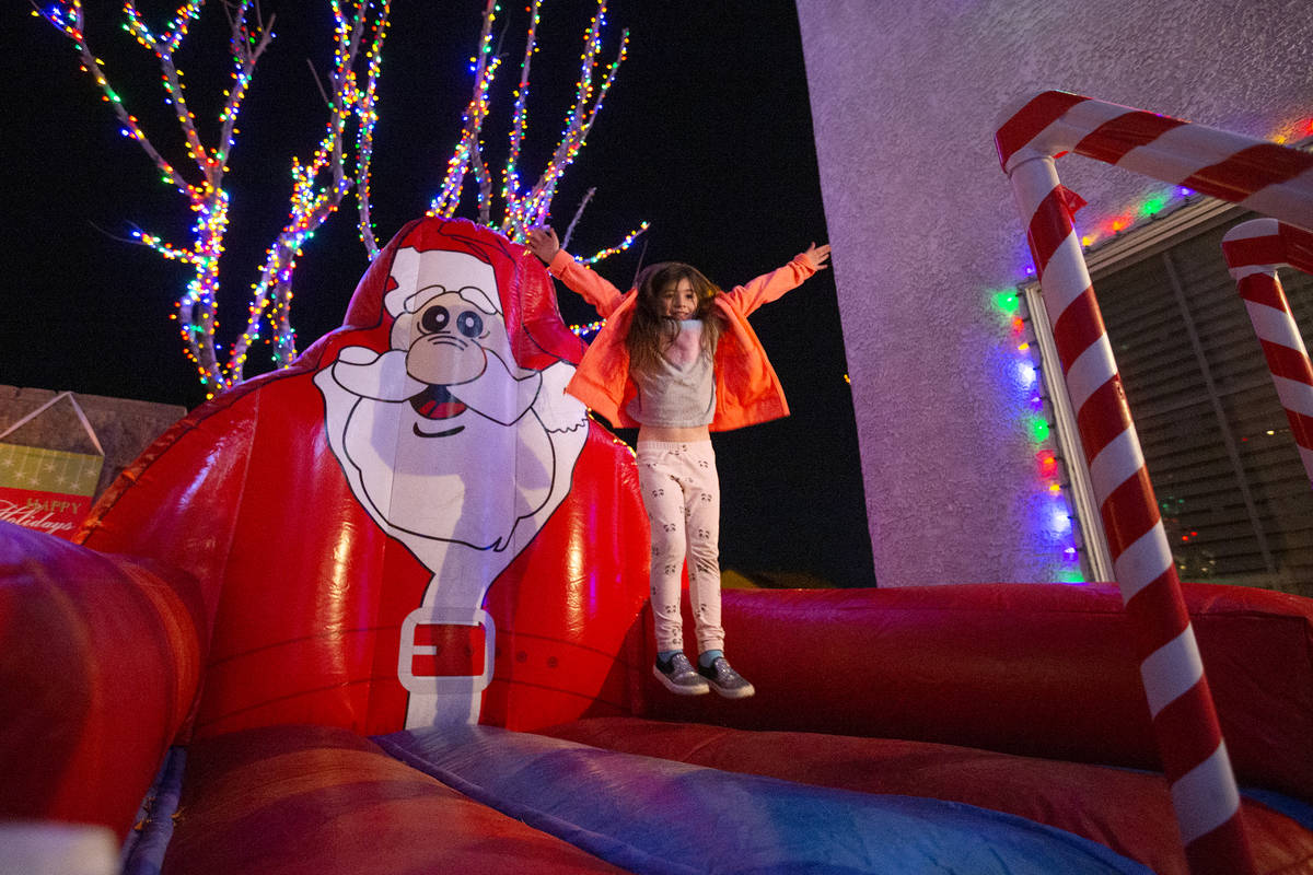 Delilah Vitone, 6, jumps on a Santa Claus bouncy toy in the backyard of Jeff and Karol Doody on ...