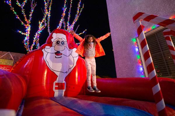 Delilah Vitone, 6, jumps on a Santa Claus bouncy toy in the backyard of Jeff and Karol Doody on ...