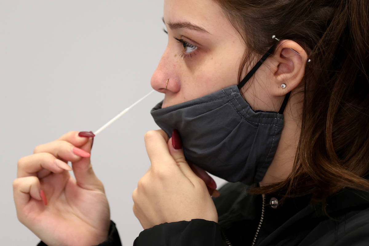 Karina Lewis of Las Vegas uses a nasal swab for a COVID-19 test on the first day of testing ope ...