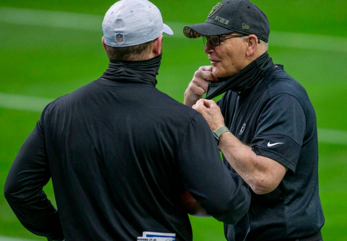 Raiders defensive line coach Rod Marinelli, right, adjusts his face mask before an NFL football ...