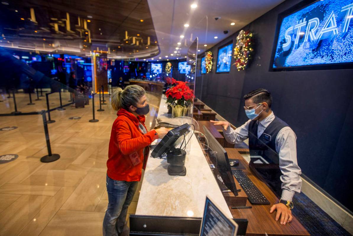 Susie Vejvoda of Scottsdale, left, with plexiglass between them, checks into the hotel with the ...