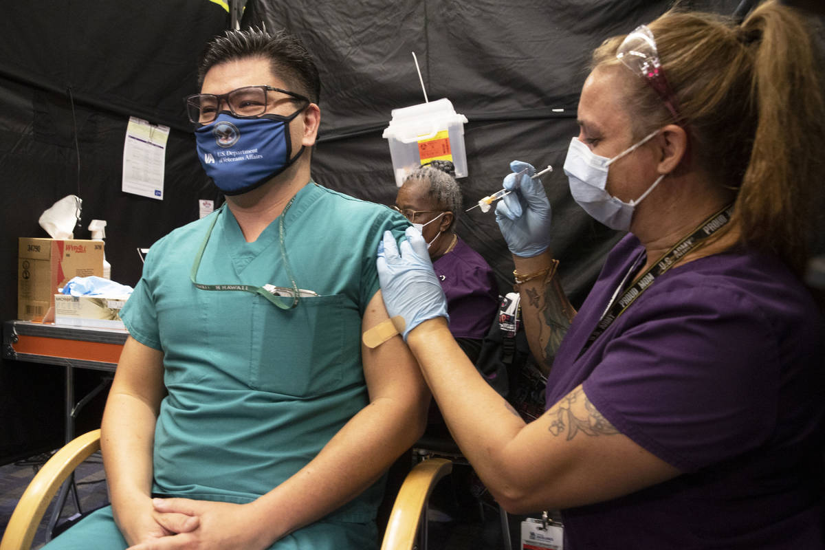 Dr. Myron Kung, left, is given the COVID-19 vaccine by nurse Darlene Roberts at the North Las V ...