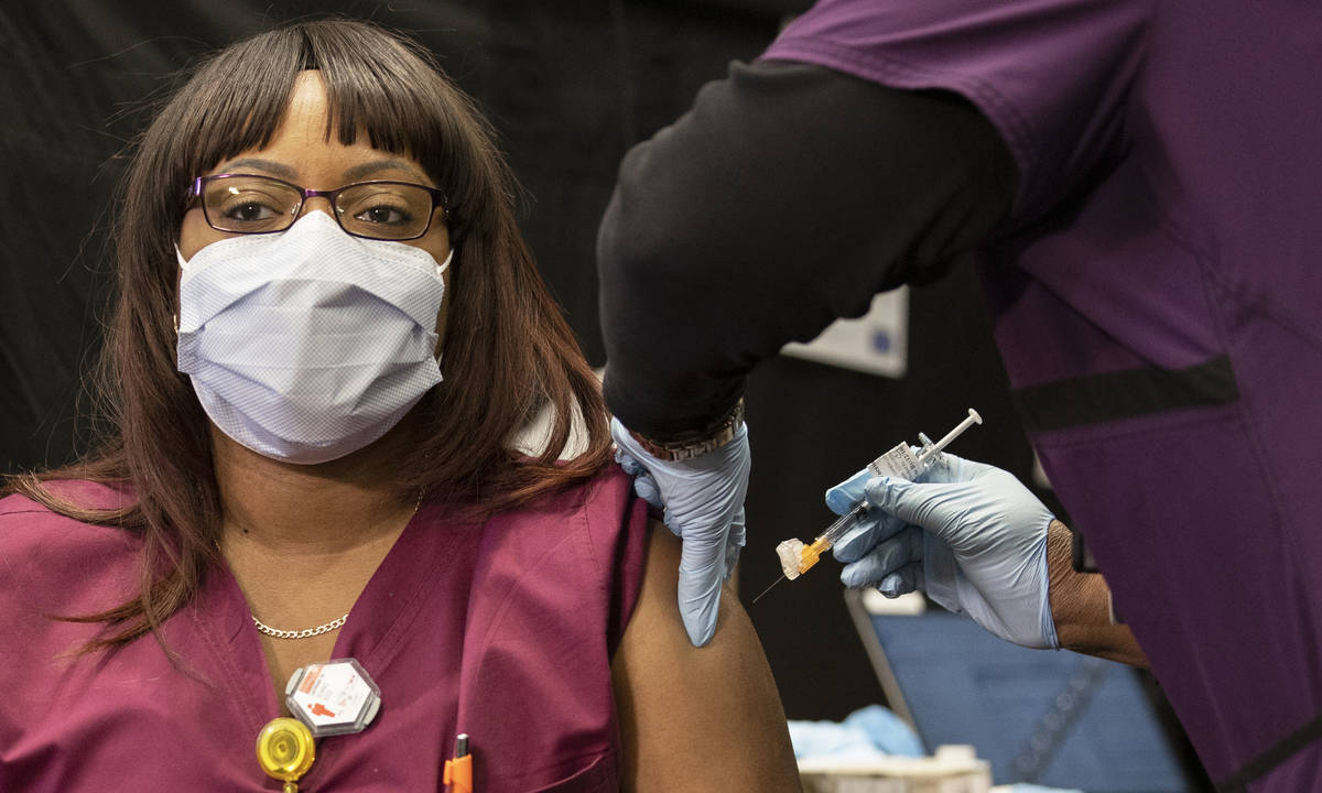 Radiology tech Remiko Ross, left, is given the COVID-19 vaccine by nurse Francine Jones-Toliver ...