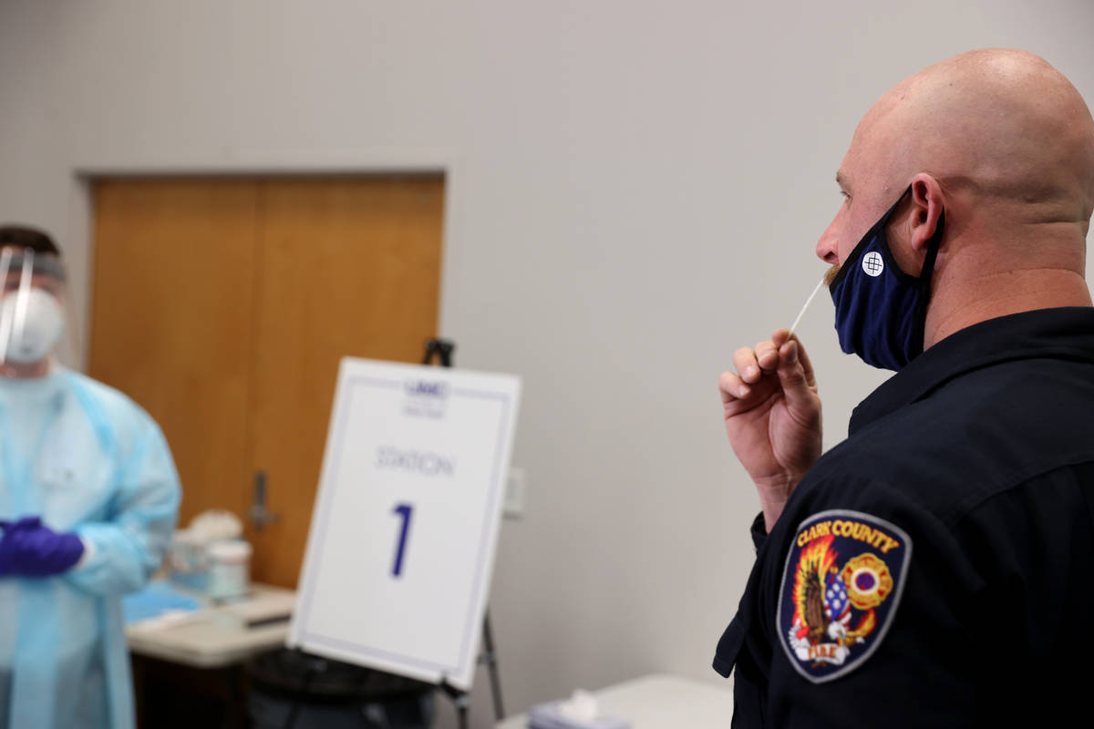 Travis Haldeman, a Clark County Fire Department engineer, uses a nasal swab for a COVID-19 test ...