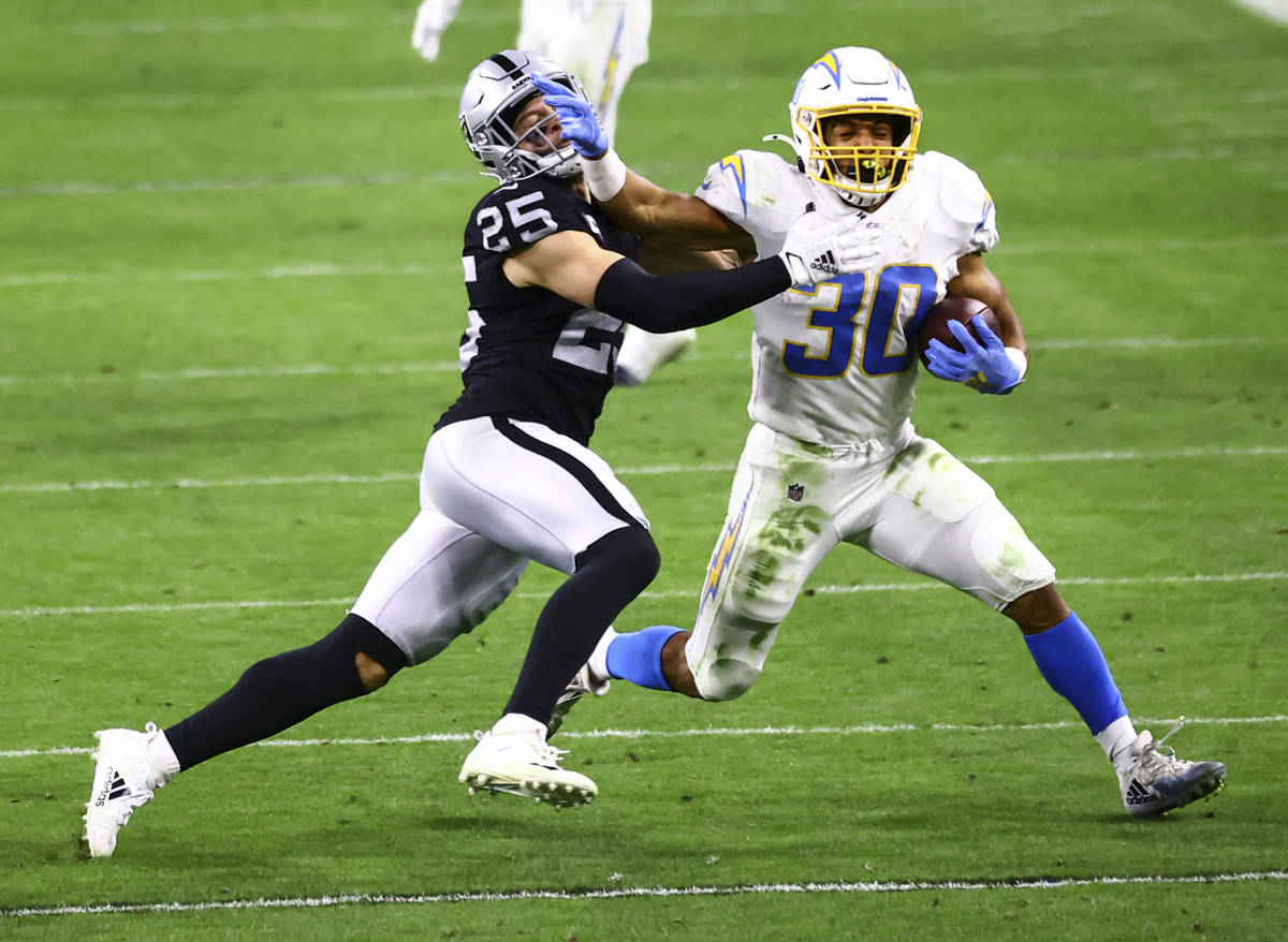 Los Angeles Chargers running back Austin Ekeler (30) runs the ball as Raiders free safety Erik ...