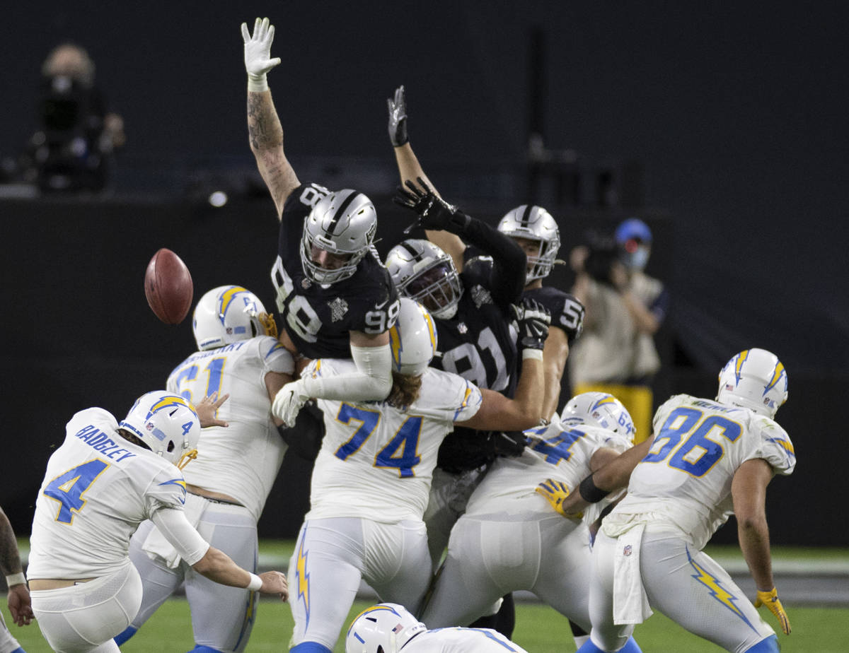 Raiders defensive end Maxx Crosby (98) and Raiders defensive tackle Kendal Vickers (91) leap to ...