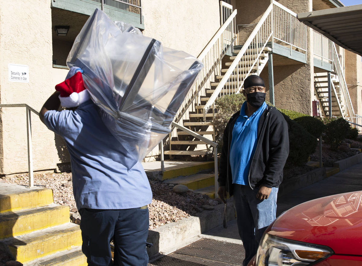 Carl Andrews, right, watches as his new furniture is delivered by Walker Furniture to his Las V ...