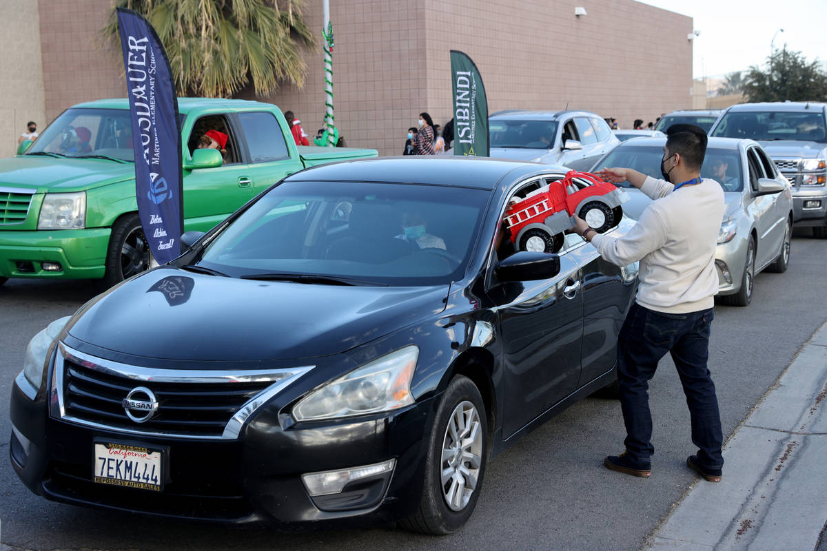 Teacher Edwin Hernandez hands out gifts at Martinez Elementary School in North Las Vegas Thursd ...