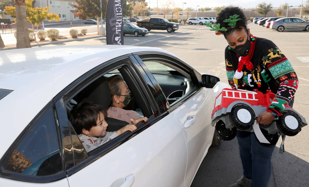 Vice Principal Frances Lucero delivers toys to Guillermo Adrian-Favela at Martinez Elementary S ...