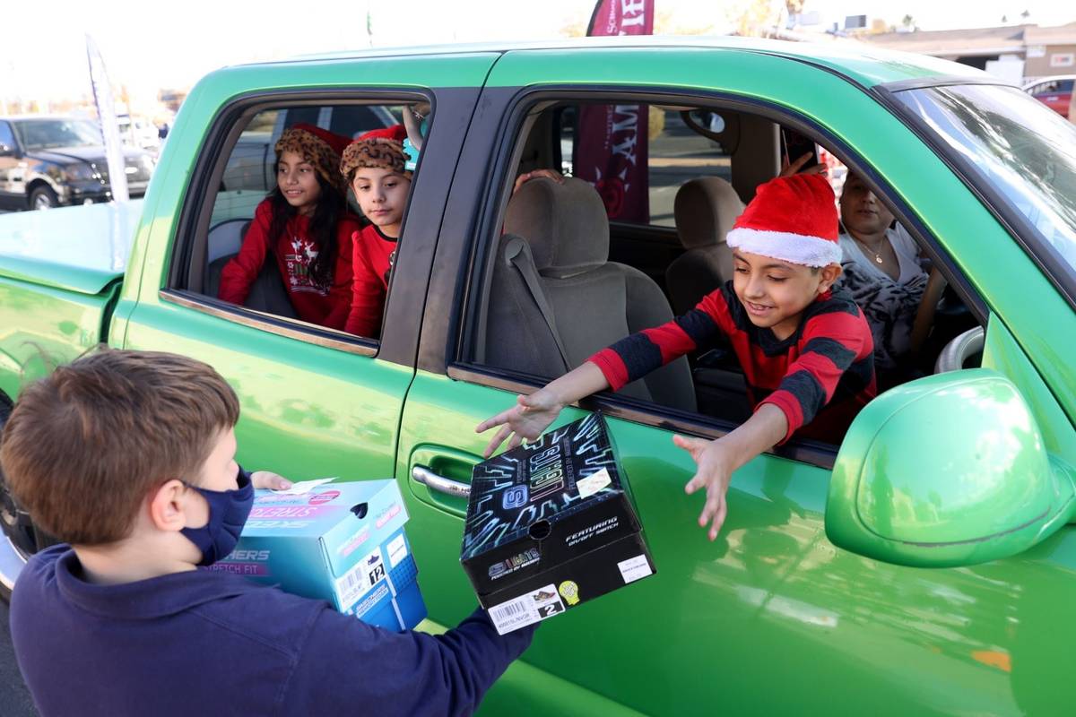 Volunteer Samuel Drobkin-Ross, 9, hands out gifts to siblings, from left, Kendra, 7, Kimberly, ...