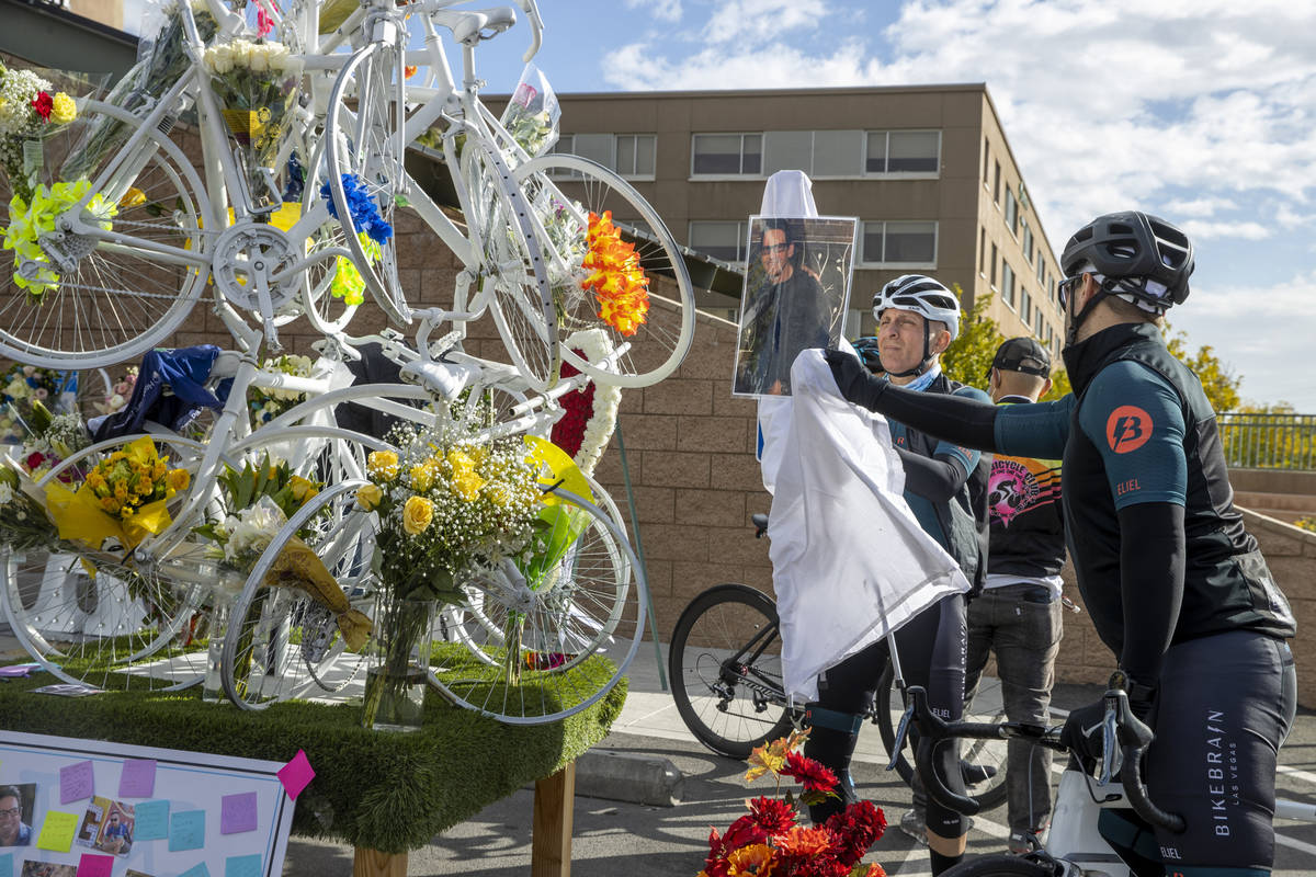 Cyclists Jim Brittelli, center, and Aaron Zastrow adjust a photo of friend Michael Murray at a ...