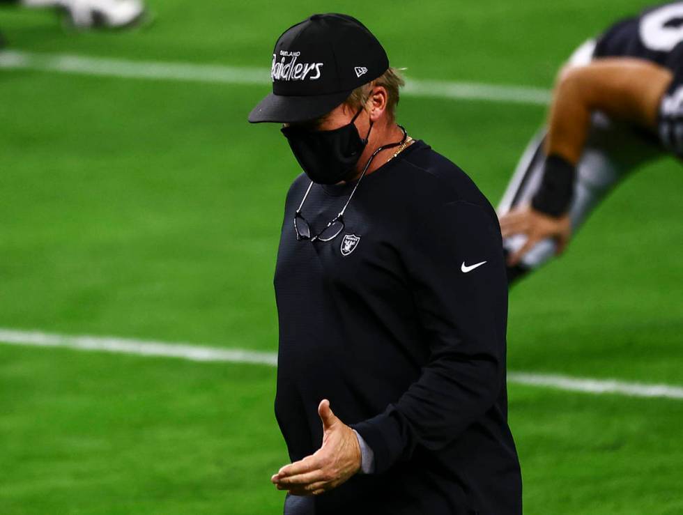 Raiders head coach Jon Gruden, wearing an Oakland Raiders hat, greets players as they stretch b ...