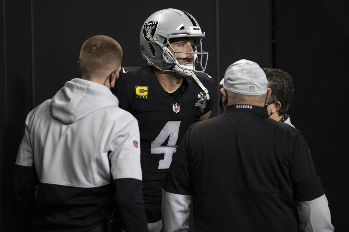 Raiders quarterback Derek Carr (4) is attended to by training staff after getting hurt scrambli ...