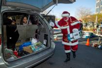 Santa Claus loads up gifts during the first NLVPD Holiday Toy Giveaway drive-thru event in the ...
