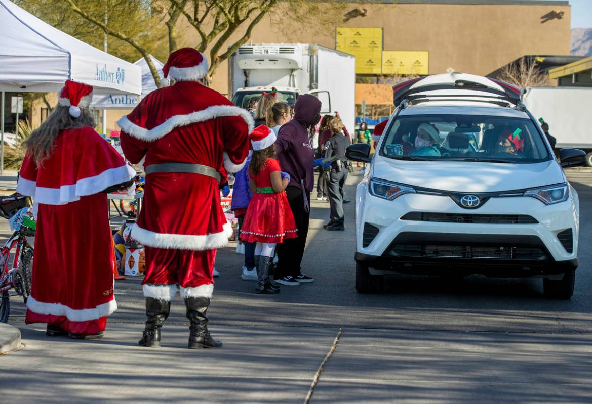 Santa and Mrs. Claus greet drivers during the first NLVPD Holiday Toy Giveaway drive-thru event ...