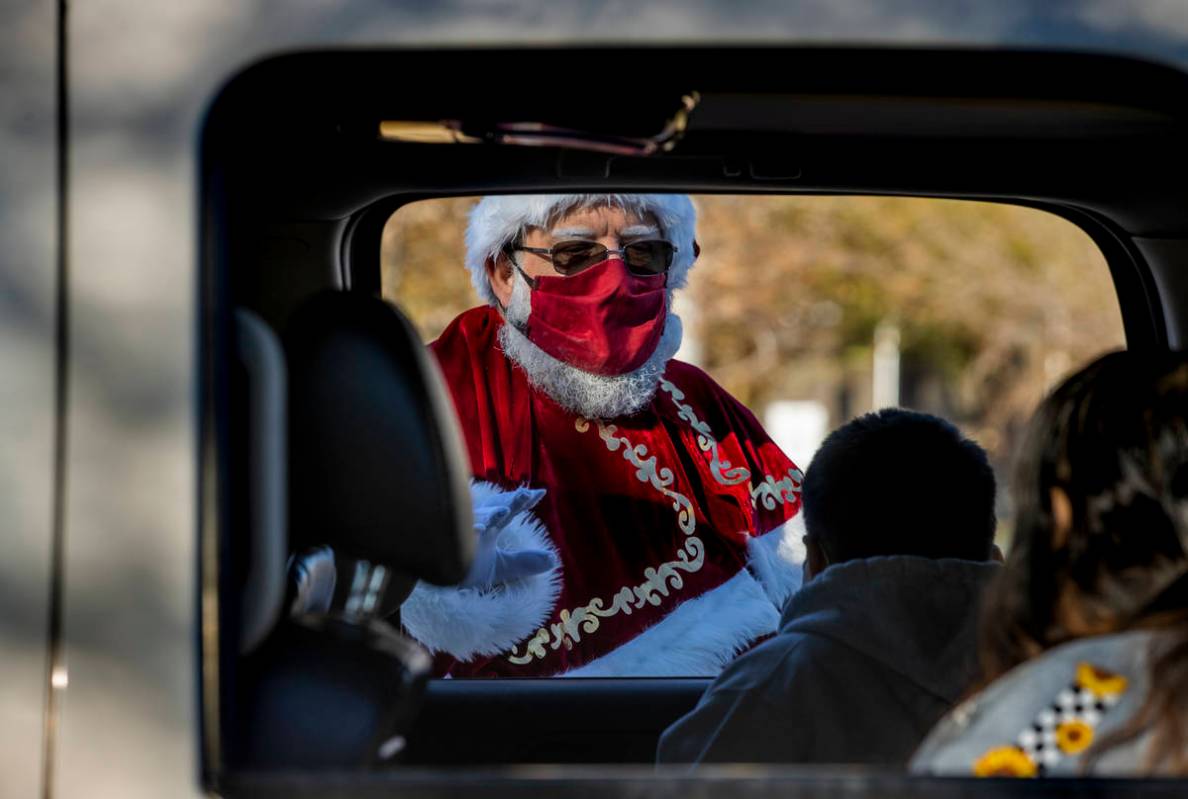Santa Claus greets passengers during the first NLVPD Holiday Toy Giveaway drive-thru event in t ...