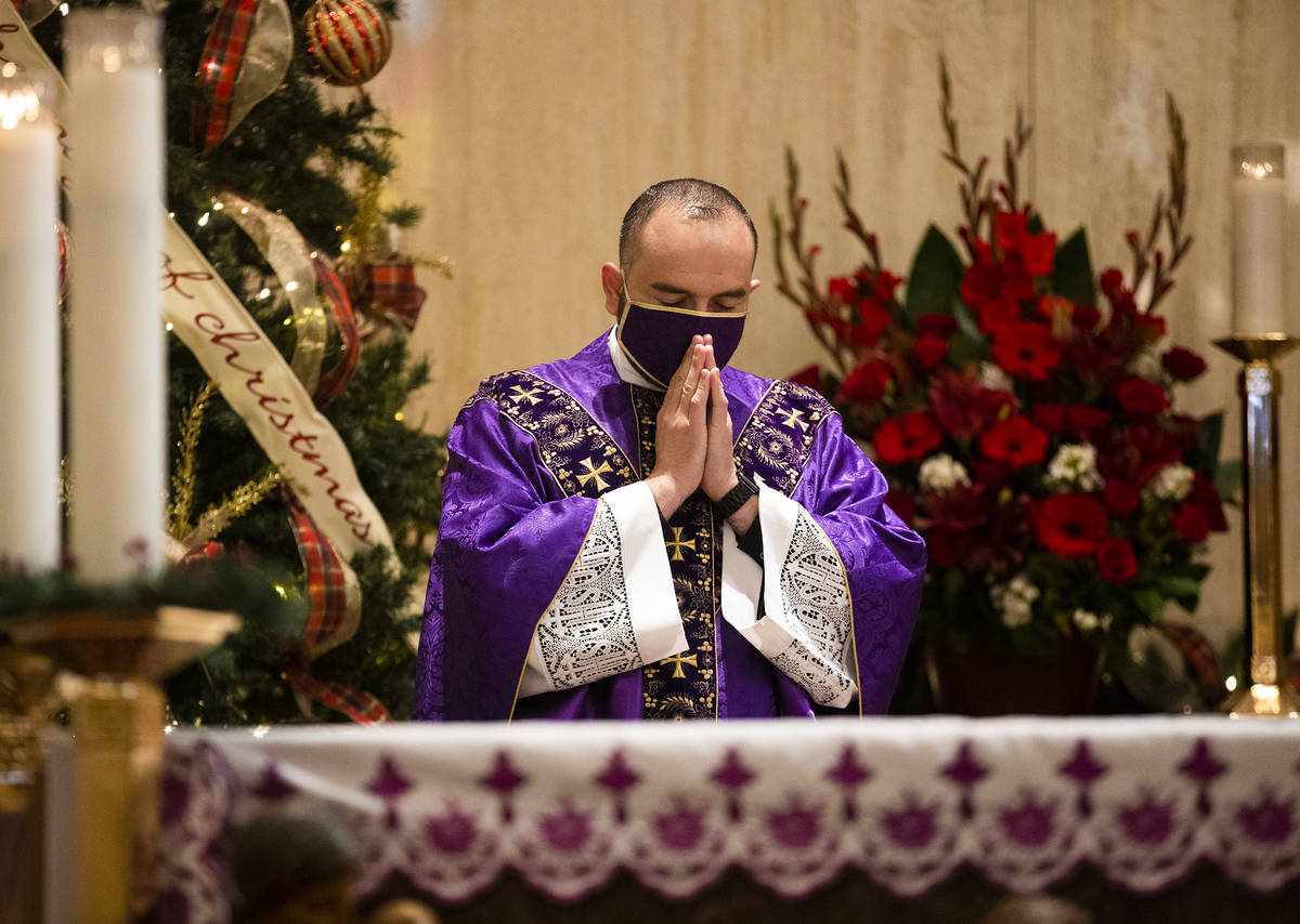 Father Miguel Corral prays during Mass at St. Anne's Catholic Church in Las Vegas, Sunday, Dec. ...
