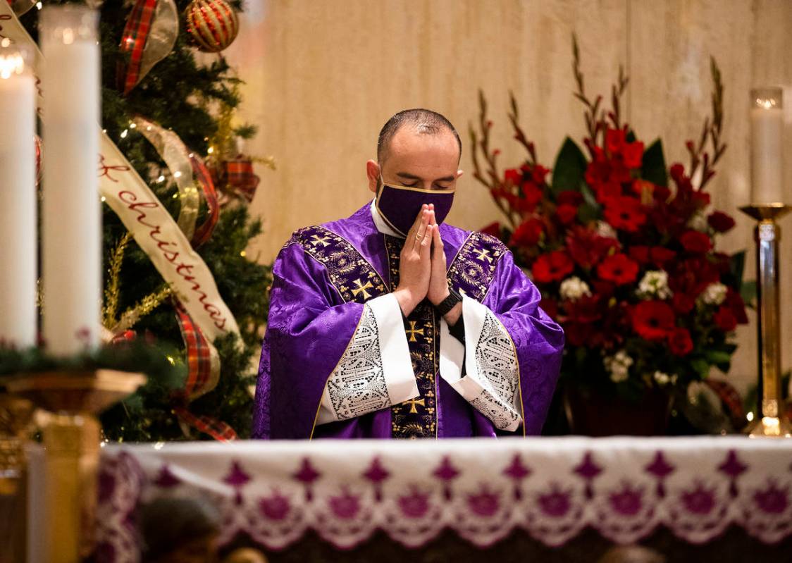 Father Miguel Corral prays during Mass at St. Anne's Catholic Church in Las Vegas, Sunday, Dec. ...