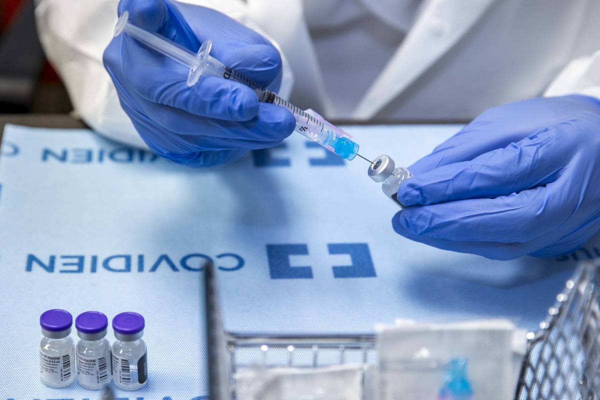 Student pharmacist Wilbur Quimba loads up new syringes with vaccine as University Medical Cente ...