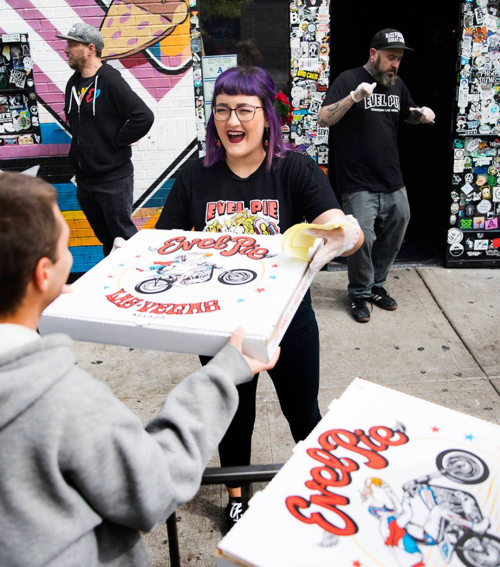 Employee Aly Bosnos hands out free pizza at Evel Pie in Las Vegas March 18, while clearing out ...