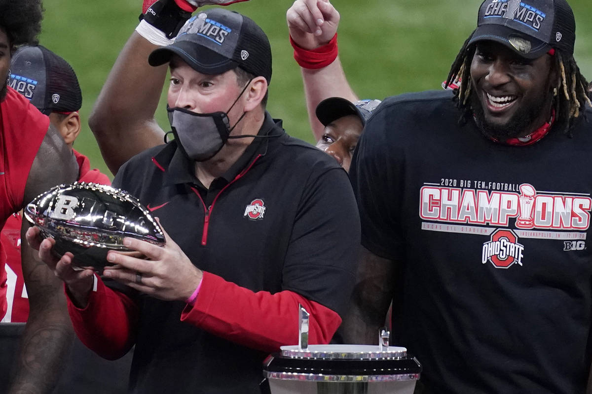 Ohio State head coach Ryan Day, left, holds the trophy along side running back Trey Sermon afte ...
