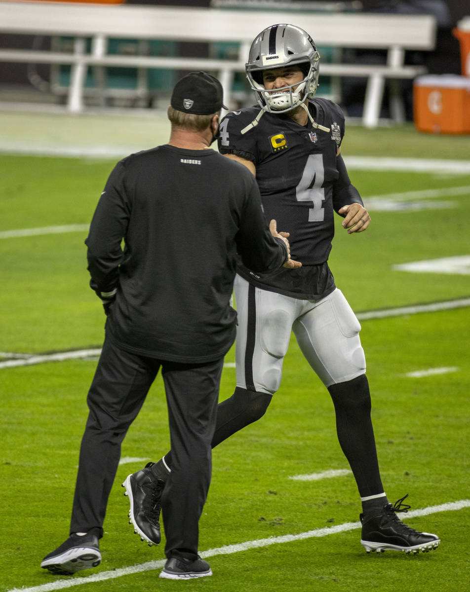 Raiders quarterback Derek Carr (4, right) greets head coach Jon Gruden during warm ups before a ...