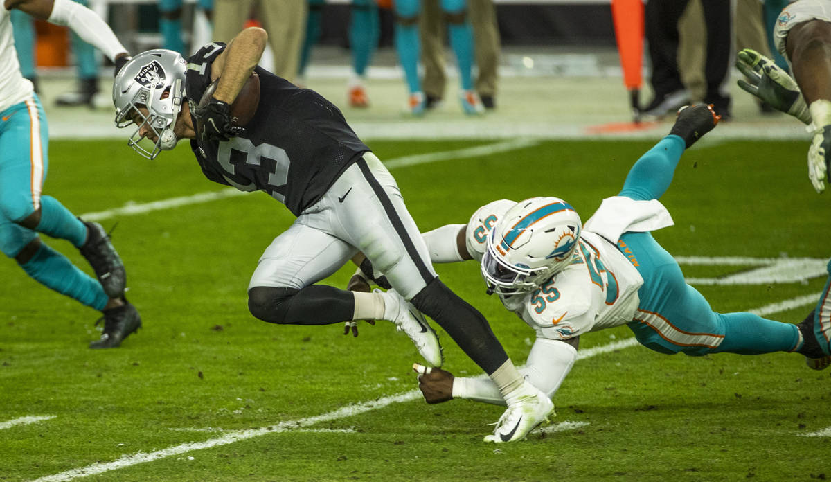 Raiders wide receiver Hunter Renfrow (13) is tripped up from behind by Miami Dolphins outside l ...