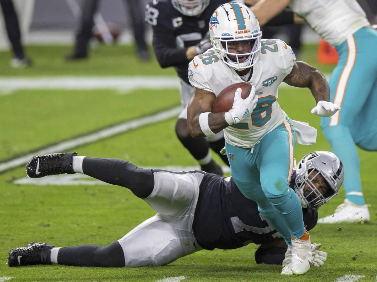 Miami Dolphins running back Salvon Ahmed (26) breaks the tackle of Raiders defensive tackle Mau ...