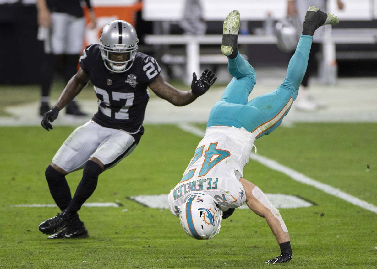 Miami Dolphins defensive back Clayton Fejedelem (42) is up ended after making a catch by Raider ...