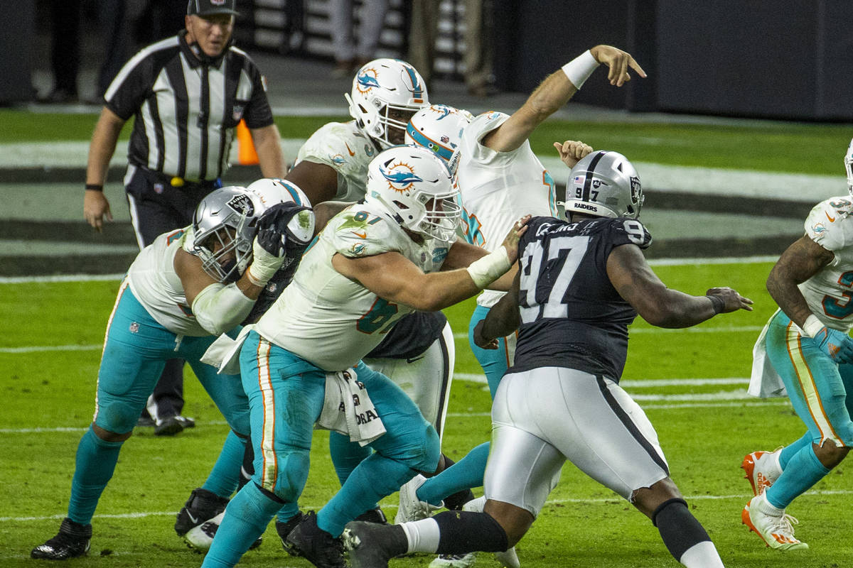 Miami Dolphins quarterback Ryan Fitzpatrick (14) gets his facemark pulled by Raiders defensive ...