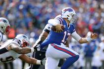 Buffalo Bills quarterback Josh Allen tries to break free from the grasp of of New England Patri ...