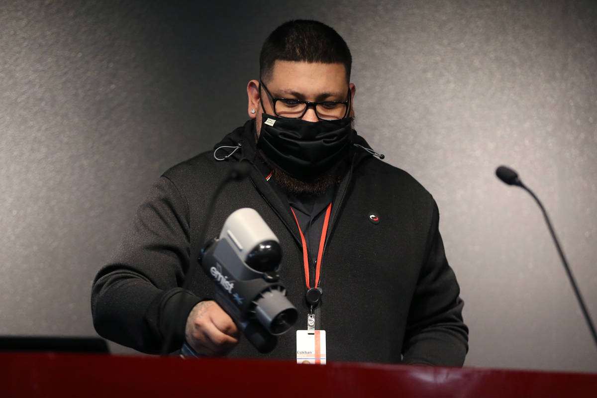 Switch employee Esteban Rocha sanitizes the podium during a press conference to discuss New Yea ...